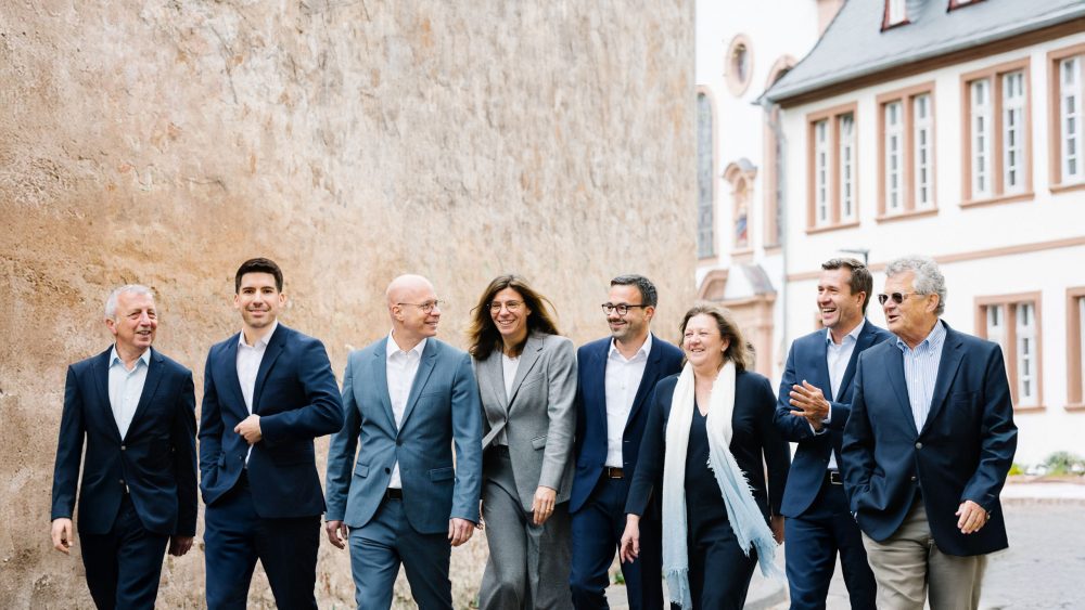 Acht Partner von Dr. Widdau & Partner stehen gemeinsam vor einer historischen Fassade in Trier.