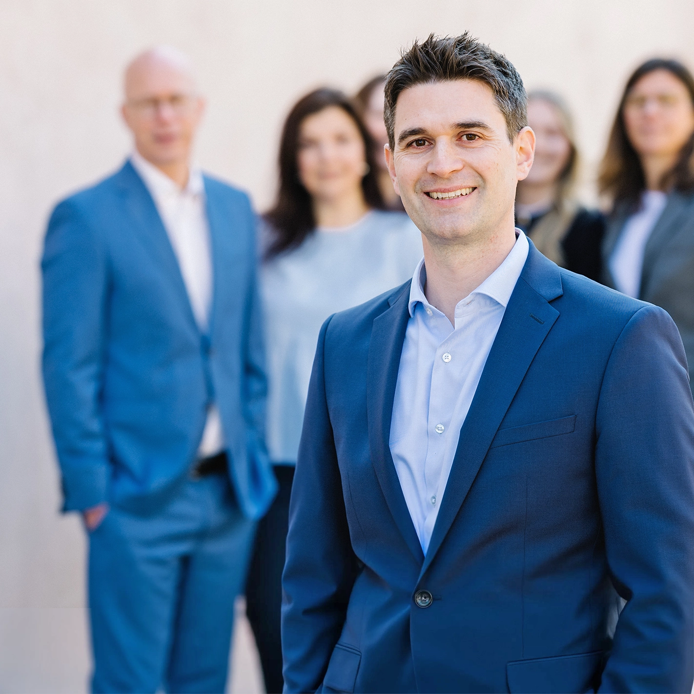Lächelnder Mitarbeiter von Dr. Widdau & Partner im Vordergrund, dahinter weitere Mitglieder des Teams.